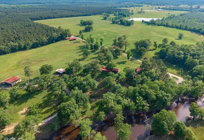 Expansive rural property featuring lush pastures, scenic water views, and multiple outbuildings for versatile use.