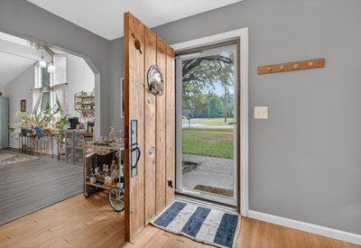 Welcoming entryway featuring a solid wooden door, leading to an inviting, open living space with abundant natural light.