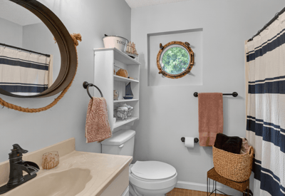 Bright bathroom featuring modern fixtures, a unique round window, and ample storage for convenience.