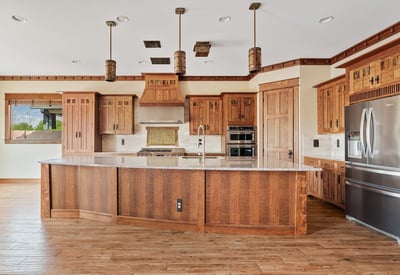 Rich wood cabinetry, detailed millwork, built-in appliances, and a striking range hood define this custom kitchen, delivering both visual appeal and everyday practicality in this Phoenix home.
