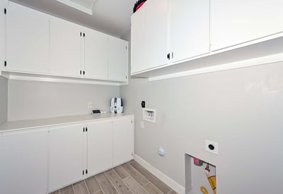 Maximize utility in this spacious laundry area with abundant built-in cabinetry, work surface, and durable tile flooring for easy maintenance.