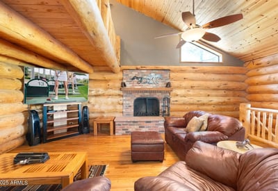 Stunning stone fireplace paired with vaulted ceilings and log construction, creating a cozy yet dramatic focal point in the main living area.