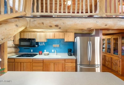 Detailed kitchen view highlighting natural wood cabinetry, gas cooking, and stainless steel appliances that blend rustic charm with modern convenience.