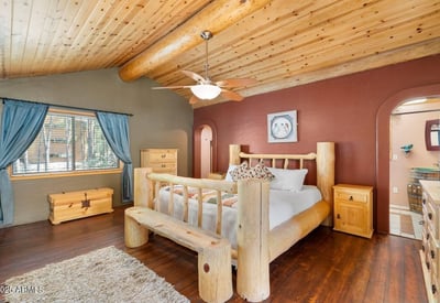 Spacious primary bedroom showcasing vaulted ceilings, rustic log craftsmanship, and an open loft-style overlook that adds character and architectural interest.