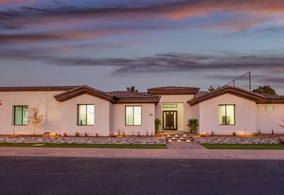 At dusk, the home glows with exterior lighting and elegant curb appeal, creating a warm welcome in this golf course community.