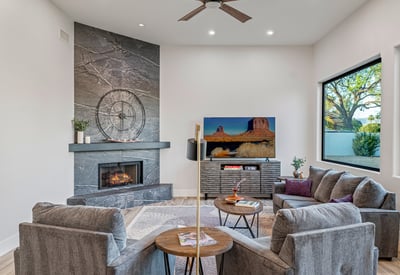 A welcoming family room with stone fireplace, large windows, and stylish finishes offers comfort and charm in Scottsdale.