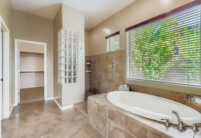 En-suite bath includes a soaking tub, walk-in shower, and oversized windows, creating a luxurious retreat at home.