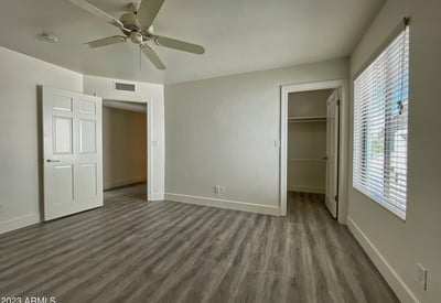 Relaxing bedroom with soft neutral tones, ceiling fan, and ample closet storage, offering comfort and tranquility.