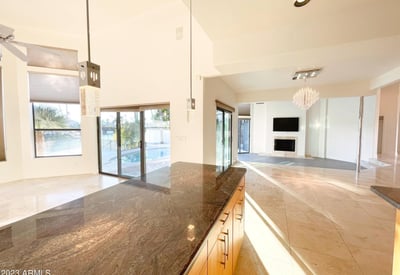 Gourmet kitchen with open flow into living area. Refined pendant fixtures and granite surfaces define this bright, upscale space.