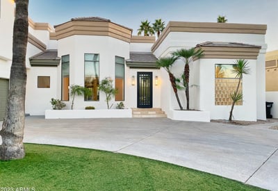 Striking entryway with tall windows, modern iron door, and smooth stucco finish for a sophisticated curb presence.