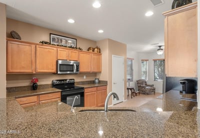 The kitchen shines with durable granite countertops, stainless fixtures, and warm tones offering both elegance and easy maintenance for Arizona living.