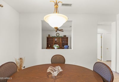 A modern dining area framed by crisp white walls and elegant lighting, offering a clear view into the private home office beyond.
