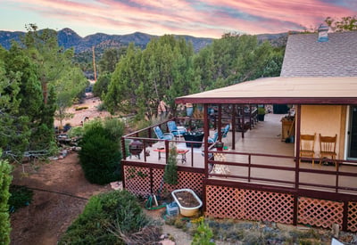 Relax on the spacious deck overlooking rolling Hackberry hills, mature pines, and painted sunsets. This outdoor oasis captures the property s serene mountain-view atmosphere.