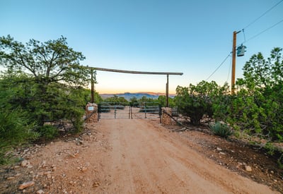 With mountains rising in the distance and clear desert skies overhead, this entry view showcases the peaceful and secluded setting of this Hackberry acreage.