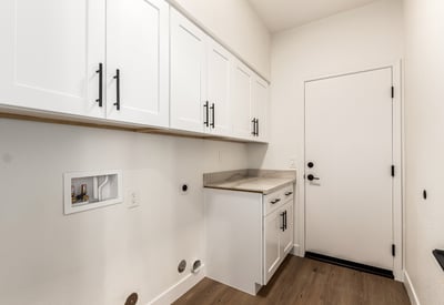 Well-designed Scottsdale laundry room featuring overhead cabinets, counter space, and washer/dryer hookups. The organized layout provides convenient storage and everyday functionality for household tasks.