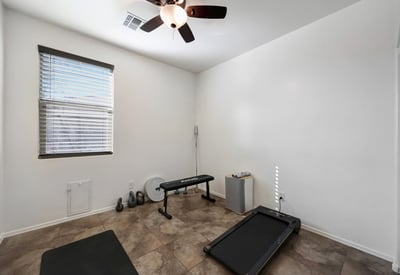 Bright secondary bedroom with carpet flooring and ceiling fan, offering comfortable living or work-from-home flexibility.