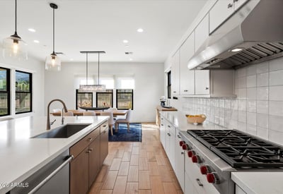 Contemporary kitchen and dining space with quartz countertops, statement lighting, and an open layout. Perfect for everyday living and entertaining in this Scottsdale luxury home.