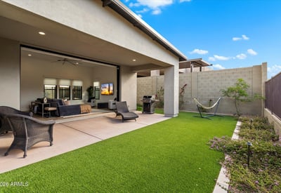 Backyard designed for entertaining with sliding glass doors, patio space, and turf lawn. Enjoy seamless indoor-outdoor living in Scottsdale.