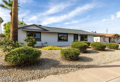 Easy-care desert landscaping with mature shrubs and a spacious driveway highlights the practical curb appeal of this well-maintained single-level Phoenix property.