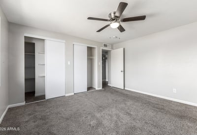 Bright guest bedroom featuring updated carpet, ceiling fan, and clean neutral tones flexible space that fits many needs in this Phoenix home.