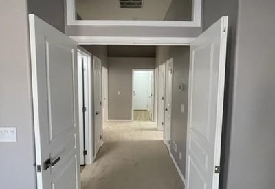 Dedicated entry hallway with double doors creating a private transition into the primary suite. Enhances privacy and overall flow of the home.
