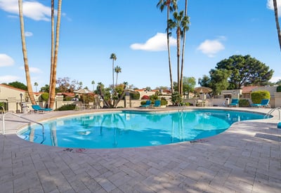 Resort-style pool surrounded by lounge seating and mature landscaping, creating a relaxing atmosphere for residents.