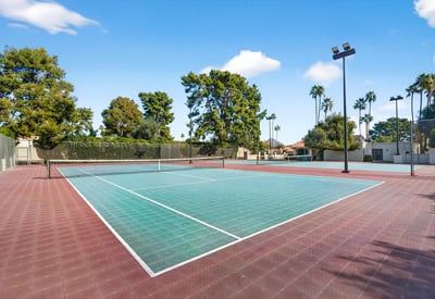 Community tennis courts surrounded by mature trees, offering a convenient recreational feature close to home.