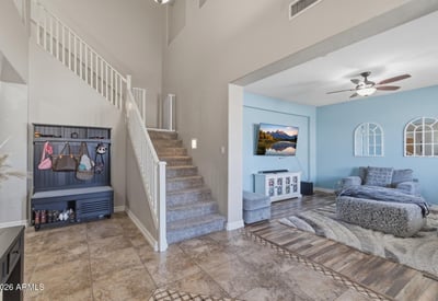 Welcoming entry foyer with soaring ceilings, tile flooring, and staircase leading to the loft and upper living areas of this spacious Queen Creek home.