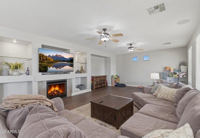 Comfortable great room with fireplace centerpiece, built-in shelving niches, and wood-style flooring, creating a welcoming space for relaxing or entertaining guests.