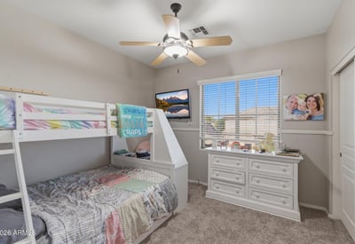 Cozy secondary bedroom with bunk bed arrangement, neutral paint, and large window allowing natural light into the room.