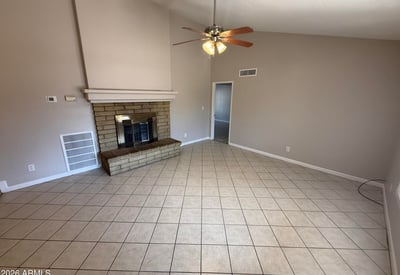 Comfortable living room featuring tile flooring, neutral colors, vaulted ceilings, and a stone fireplace centerpiece. This Glendale home provides a cozy environment for relaxing evenings.