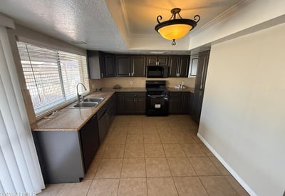 Glendale kitchen with dark cabinetry, tile floors, and ample prep space. Large window above the sink provides natural light and views toward the backyard pool area.