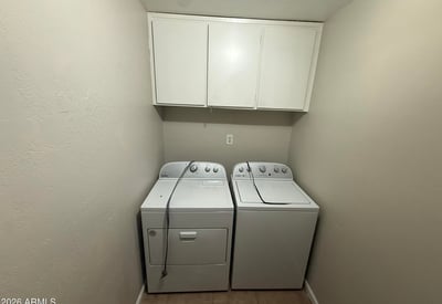 Laundry room featuring washer and dryer with built-in overhead cabinets for additional storage. Convenient layout helps keep daily household tasks organized.