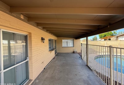 Covered patio space overlooking the fenced backyard pool area. The shaded outdoor living space is perfect for relaxing evenings or entertaining guests.
