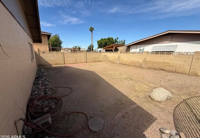 Expansive backyard area with low-maintenance desert landscaping and block wall fencing. The generous outdoor space offers flexibility for entertaining, recreation, or customizing future landscaping.