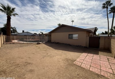 Rear exterior view highlighting the covered patio, fenced pool, and spacious yard. The layout provides a welcoming outdoor setting ideal for relaxing evenings and weekend gatherings.