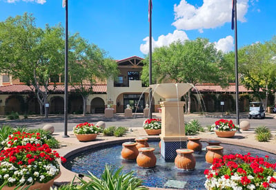 Clubhouse and fountain area surrounded by lush landscaping and mature trees. This Phoenix golf community offers a resort-style atmosphere and amenities.