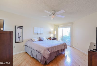Primary bedroom with natural light, ceiling fan, and sliding door access to the backyard, offering a relaxing private retreat.