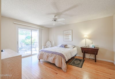 Comfortable guest bedroom with patio access, hardwood flooring, and plenty of natural light ideal for visitors or multi-use space.
