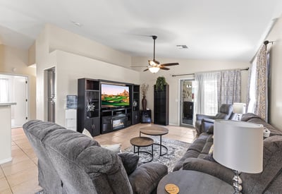 Comfortable family room with neutral finishes, ceiling fan, and open flow to kitchen and dining areas for easy living.