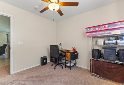 Multi-use room perfect for a home office or bedroom, featuring natural light, neutral tones, and ceiling fan.