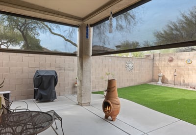 Backyard with artificial turf, covered patio, and low-maintenance design, ideal for outdoor relaxation and entertaining in Phoenix.