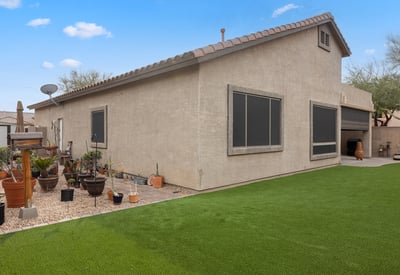Side yard with patio access and easy-care turf, offering additional usable outdoor space in this Phoenix property.