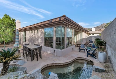 Private backyard with multiple seating areas, stone patio, and desert landscaping designed for easy upkeep in Phoenix.