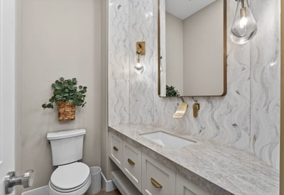 Elegant powder room with updated vanity, quartz countertop, decorative backsplash, and modern lighting in this Scottsdale residence.