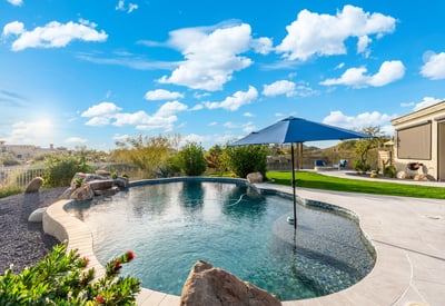 Scottsdale pool featuring built-in umbrella seating area, surrounded by pavers and landscaped yard, ideal for outdoor enjoyment.