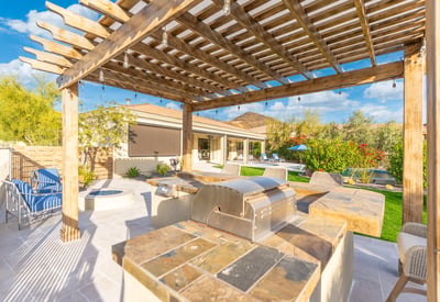 Scottsdale backyard featuring a pergola-covered outdoor kitchen with built-in grill and bar seating, ideal for entertaining guests.