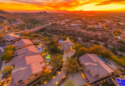 Scottsdale aerial view of the neighborhood at sunset with desert landscaping and mountain backdrops.