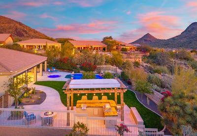Scottsdale backyard featuring a pergola-covered outdoor kitchen with built-in grill and seating, perfect for entertaining with views of the pool and desert.