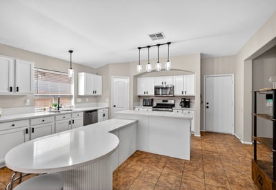 Bright open kitchen with large island, white cabinetry, and modern lighting. Perfect for entertaining and daily living in this Casa Grande home.